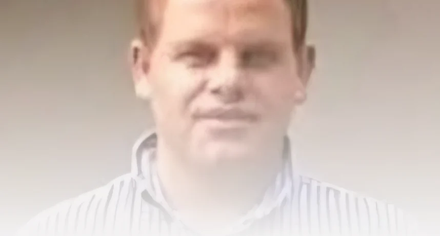 Portrait of a man wearing a light striped shirt with a soft, hazy overlay obscuring details of his face.